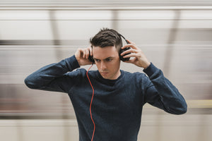 A man listening to music on headphones with a blurred bakcground